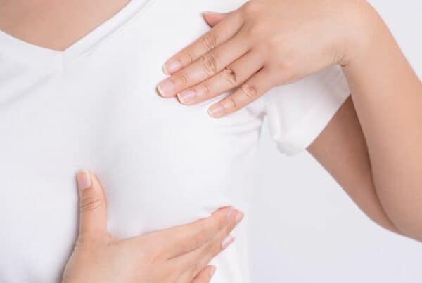 Picture of a woman wearing a tshirt and examining her breast