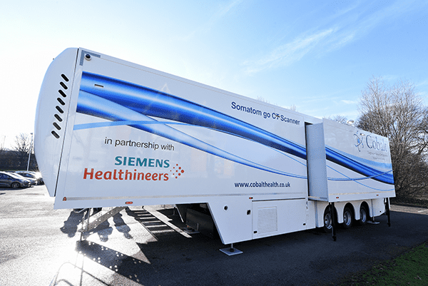An image of the van used for lung health checks in Hull. It's a large white trailer with a blue swirl design, and it features the Siemens and Healthineers logos.