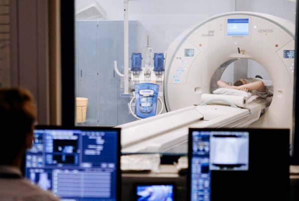 Image of CT scanner with someone sat looking at the screens in the booth