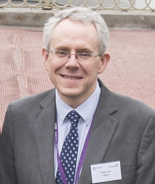 Headshot of Simon Cox, the newly-announced managing director of the Cancer Alliance. He has grey hair, wears glasses and a suit, and smiles at the camera.