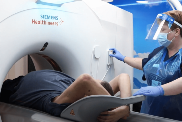 A man receiving a CT scan as part of the Targeted Lung Health Check Programme. A radiographer is pictured next to him, operating the CT scanner.