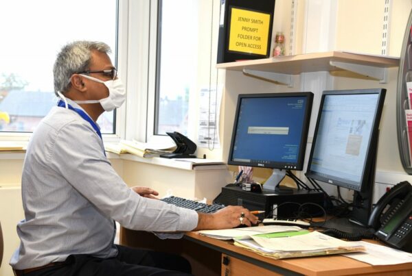 Picture of a doctor sat working on a computer in an office