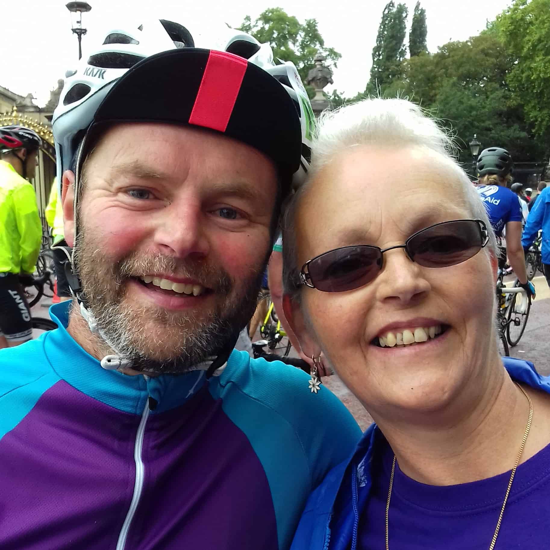 Photo of Helen and her brother at a RideLondon event. Helen is wearing a t-shirt and has short blond hair. She is wearing sunglasses. Her brother is wearing a cycling top and helmet.
