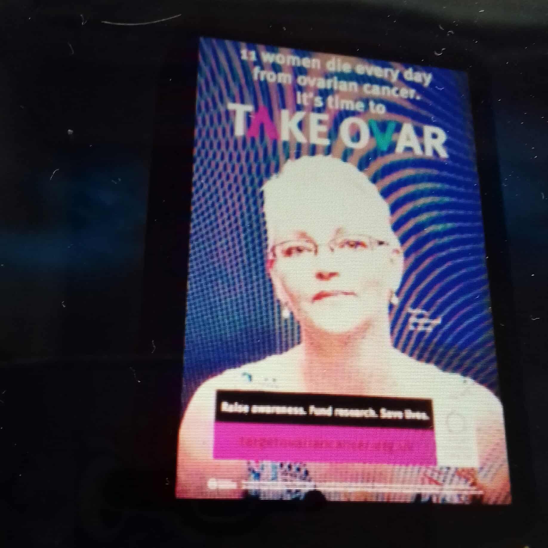 A photo of a Target Ovarian Cancer digital billboard which includes a picture of Helen. The billboard reads '11 women die every day from ovarian cancer. It's time to take ovar.