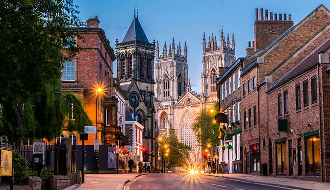 picture of a street in York at dusk with the York Minster at the bottom of the street.