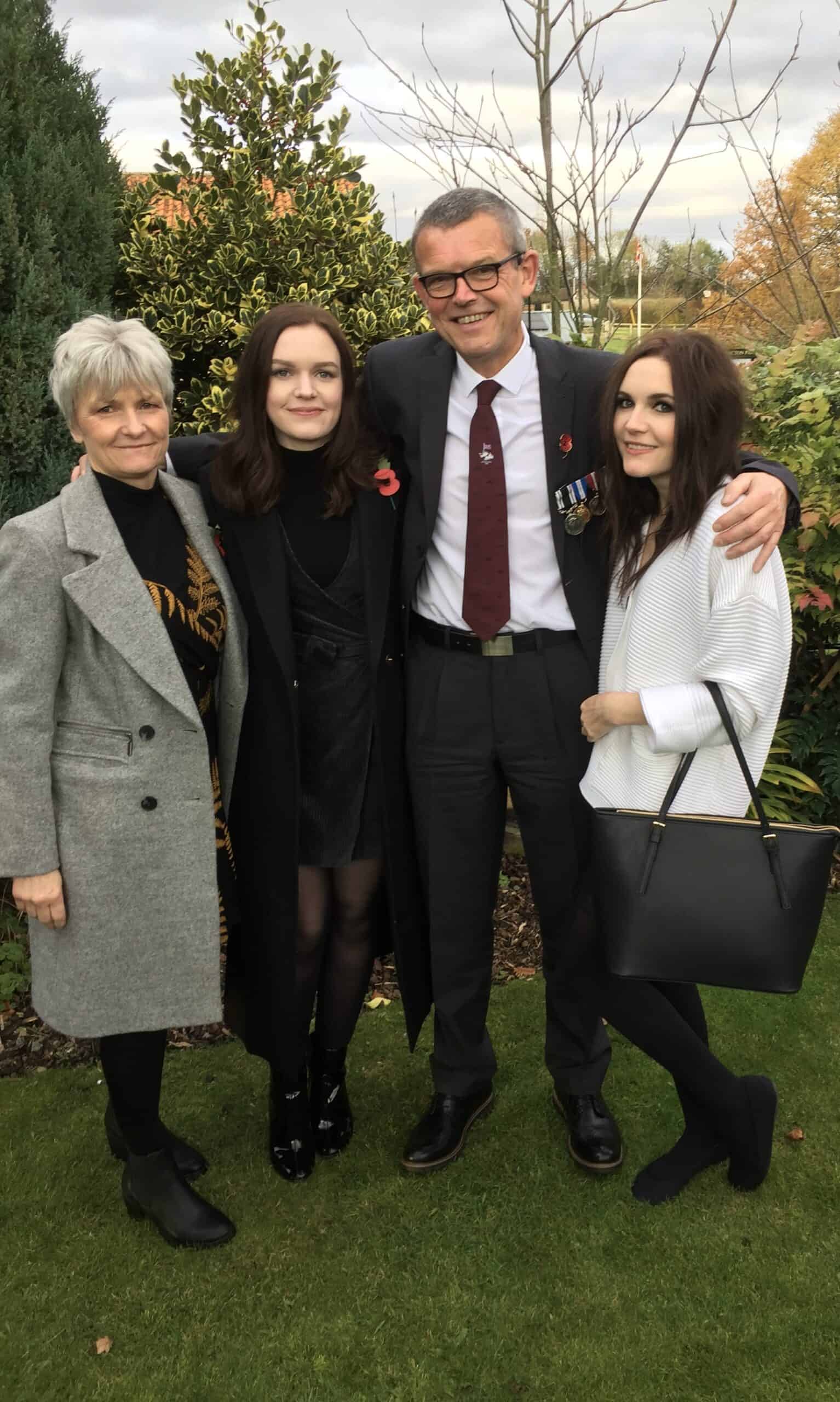 Gary, centre in darl suit with white short and red tie, with his wife and daughters stood at each side