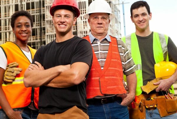 Picture of three men and a women working on a building site with hard hats and high vis tops